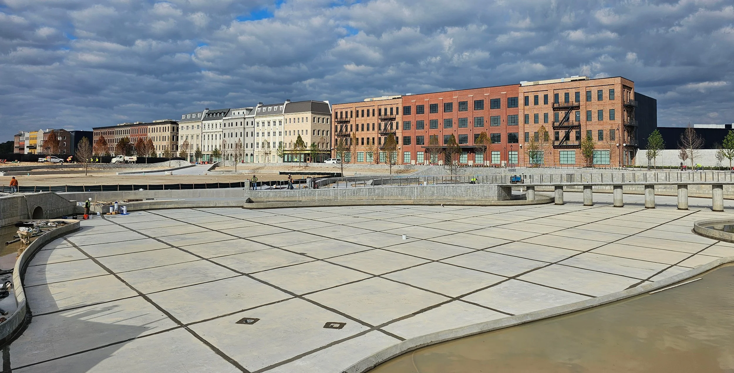 Assembly Atlanta – Final touches on public park and stormwater amenity spaces. Construction team members standing in the space show the tremendous scale of the stormwater pond.