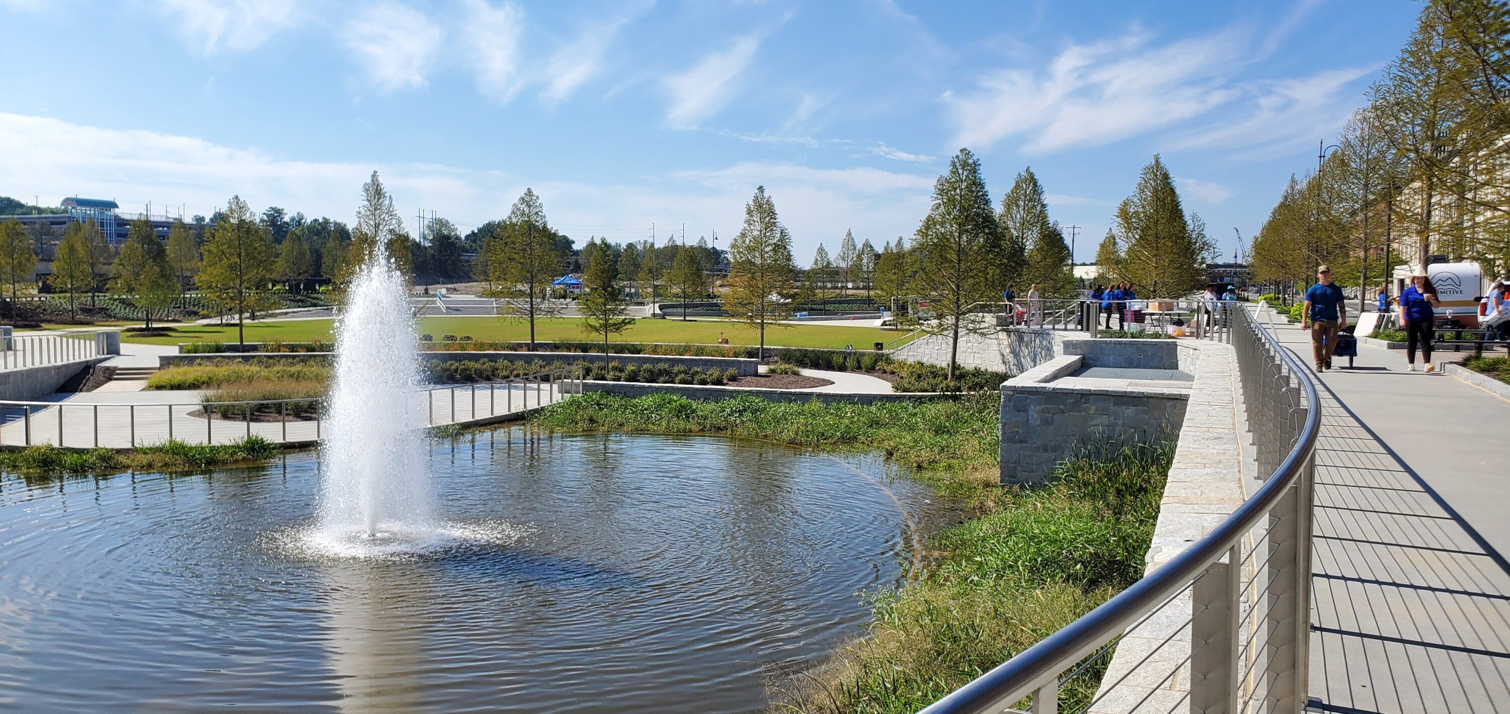 small pond with a fountain in a park with walking paths