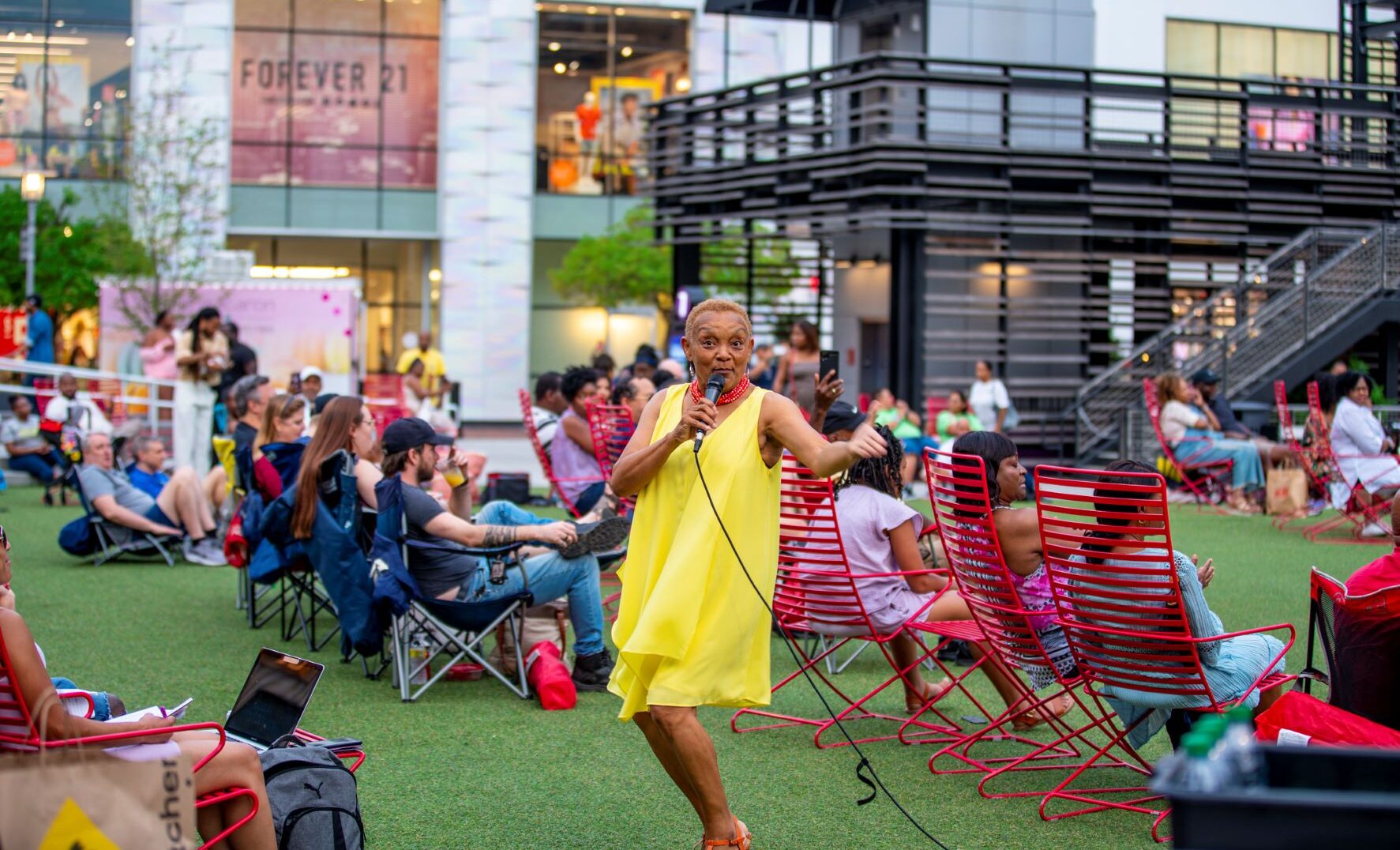 Woman in a yellow dress with a microphone in middle of Atlantic Station common area