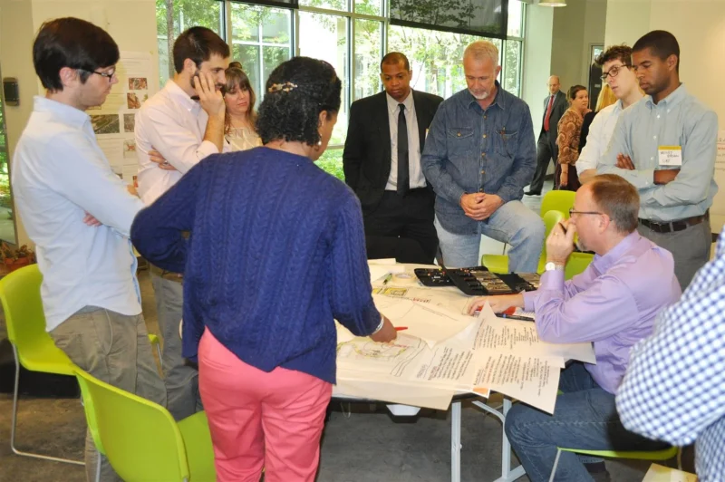 Group of people surrounding a table with lots of papers
