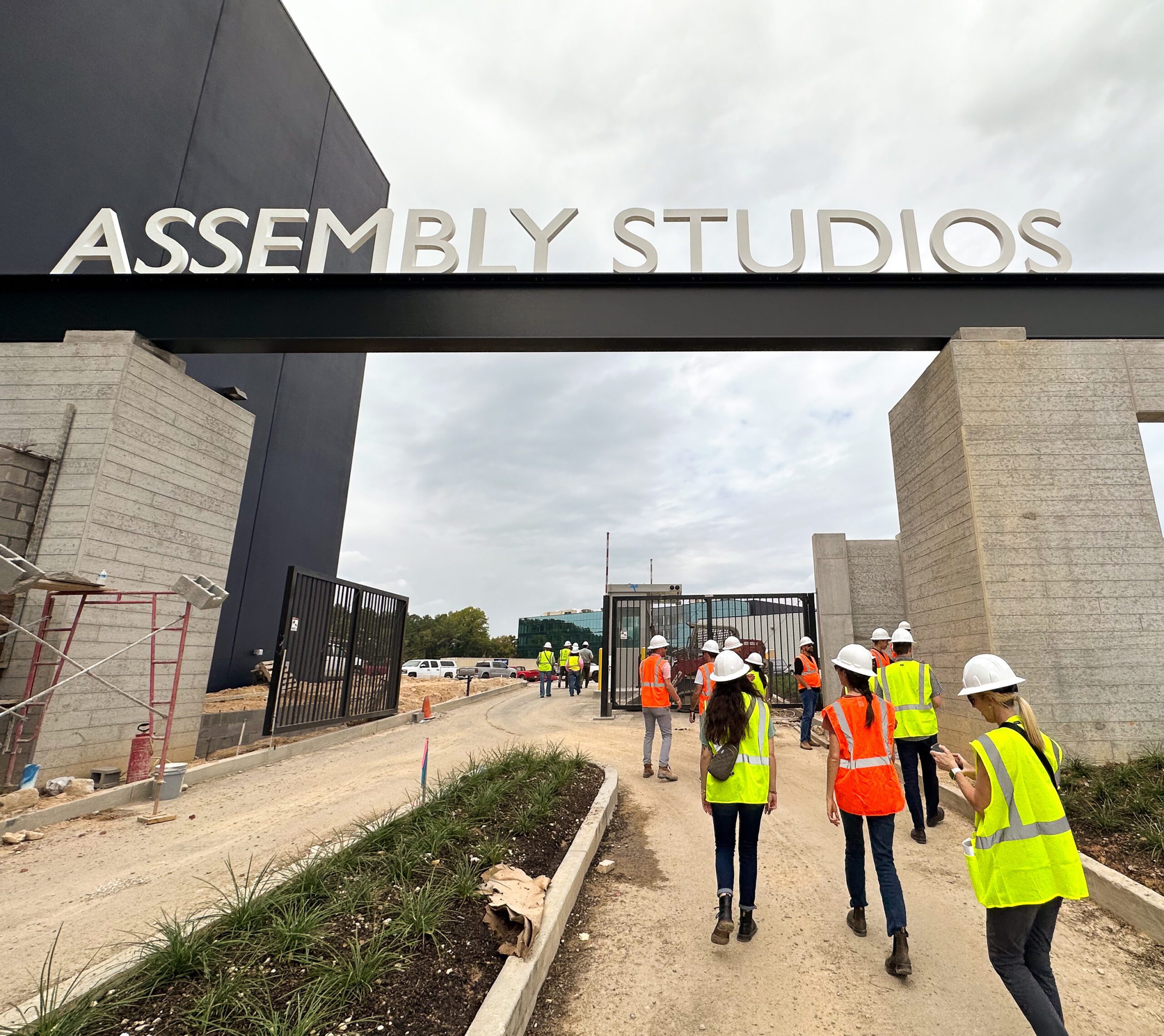 People in safety vests and hard hats walking into Assembly Studios under construction